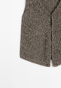 Gros plan d’un gilet en tissu tricoté marron et blanc texturé, à col en V et fermeture boutonnée devant, sur fond blanc.