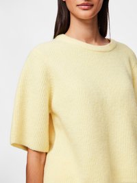 Short-sleeve, ribbed sweater in soft yellow fabric, featuring a rounded neckline and relaxed fit. Textured surface adds dimension.