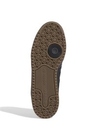 Gummisula med ett mönstrat mönster, med en brun bas och svarta accenter. Varumärkeslogotyp synlig p å sidan.