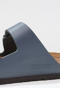 Mørkeblå Birkenstock sandal med glatt overdel, korkfotbed og svart gummisåle med preget merke på siden.