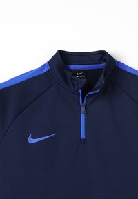 Granatowy pulower z zamkiem błyskawicznym na ćwierć z niebieskimi akcentami; wykonany z tkaniny odprowadzającej wilgoć; z małym logo Nike na piersi.