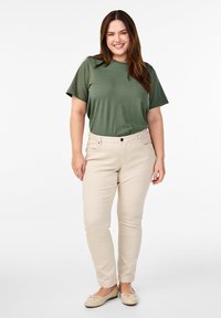 Olivengrøn bomulds t-shirt parret med beige slim-fit bukser. T-shirten har en rund halsudskæring og korte ærmer, mens bukserne har forlommer.