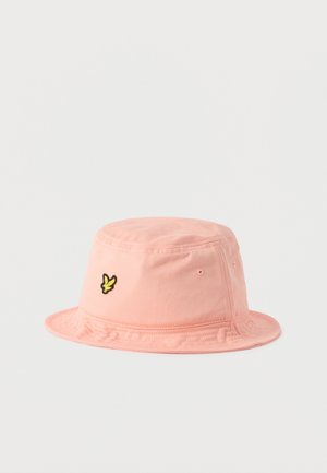 Light pink cotton bucket hat with a small yellow bird logo on the front and stitched eyelets on the sides.
