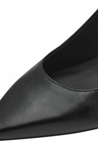 Chaussure à talon haut en cuir noir avec un bout pointu et un design à coupe basse. Texture lisse avec des détails de couture subtils le long du bord.
