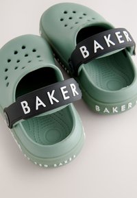 Groene rubberen klompen met een zwarte band met "BAKER" in witte letters. Geperforeerd ontwerp en een gestructureerde binnenzool voor comfort.