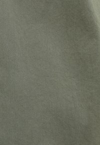 Close-up van groene stof met fijne diagonale structuur en subtiele textuurdetail.