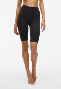 Shorts de vélo noirs en matériau extensible, présentant une taille haute, une coupe longueur genou et une surface lisse. Aucun motif visible ni quincaillerie.