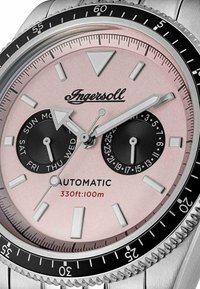 Automatyczny zegarek Ingersoll z różowym cyferblatem, czarnymi podtarcza dnia i daty, świecącymi wskazówkami oraz stalowym bezel i bransoletą.