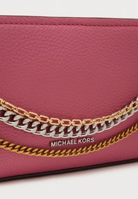 Ροζ πορτοφόλι υφασμένο από δέρμα με αλυσίδες σε ασημί, χρυσό και ορείχαλκο και ασημένιο λογότυπο Michael Kors στο μπροστινό μέρος.