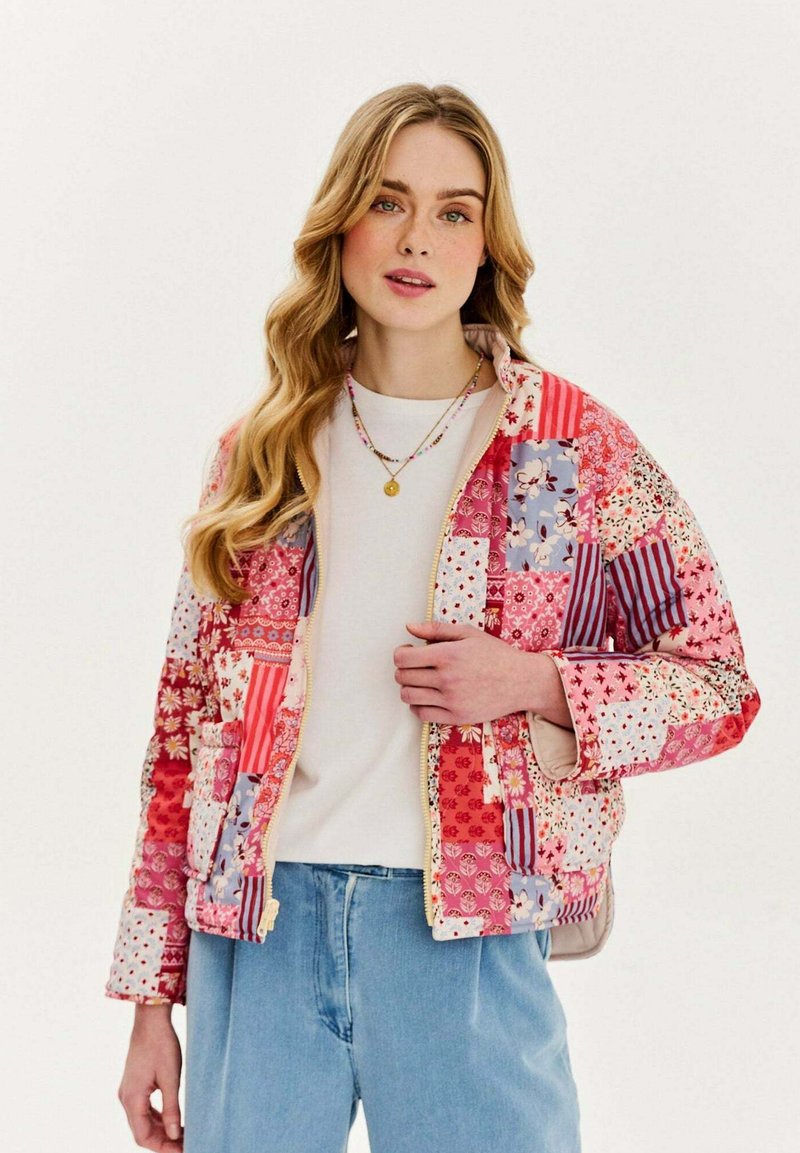 Prešívaná bunda s patchwork dizajnom v červených a ružových odtieňoch, s kvetinovými a pruhovanými vzormi, so zipsom vpredu a širokými rukávmi.