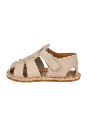 Sandalia para bebé de cuero beige con correa ajustable y diseño de punta abierta en suela con textura de corcho sobre fondo blanco.