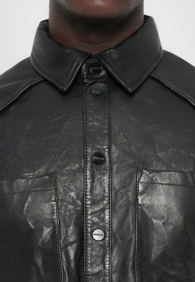 Black leather shirt with a structured collar, featuring a front button closure and two patch pockets. Smooth texture with a slight sheen.