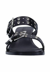 Sandales plates noires avec de larges lanières ornées de œillets en argent et de boucles. Semelle intérieure lisse et minimaliste pour un confort optimal.