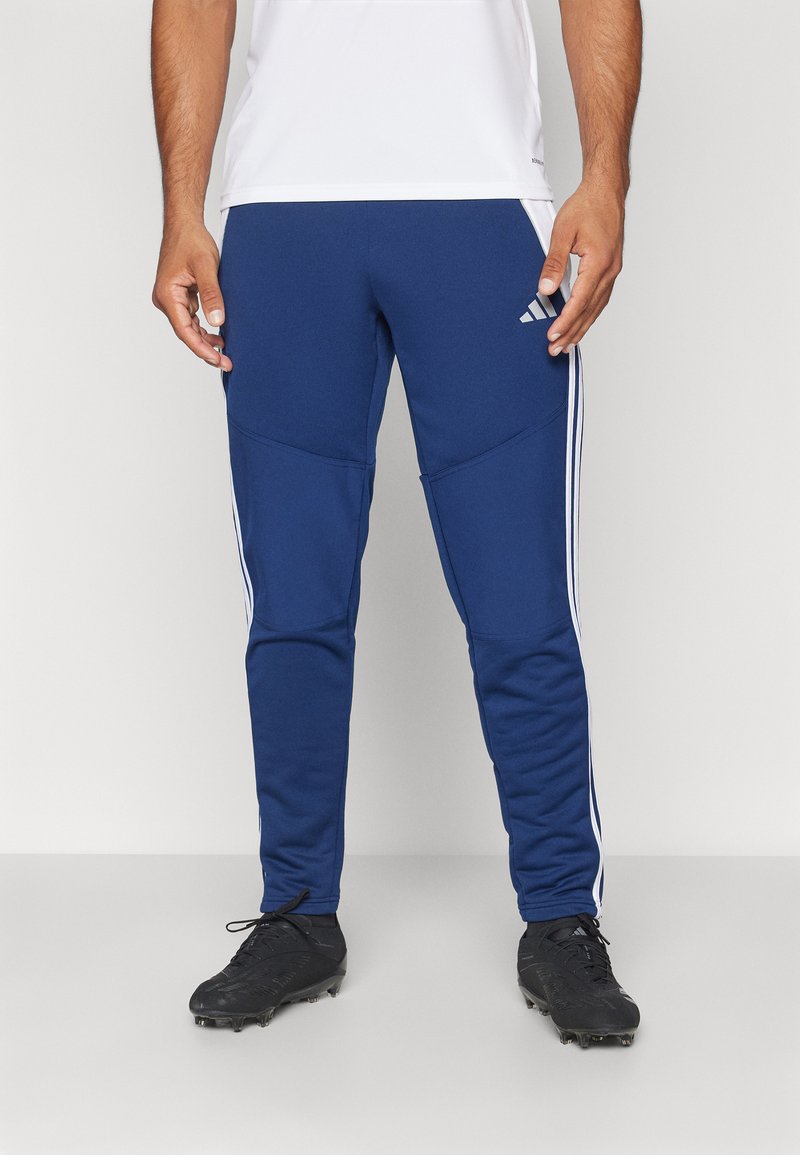 Marineblaue Sporthose mit weißen Seitenstreifen, tailliertem Design und glatter Textur. Mit Adidas-Logo auf der Vorderseite.