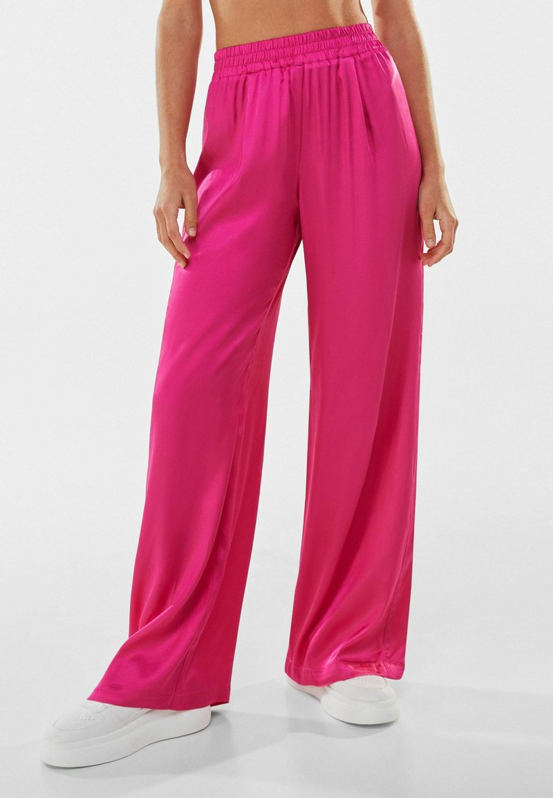 Pink satin wide-leg pants with an elastic waistband and flowing fabric. Subtle sheen, lightweight texture, and a relaxed fit.