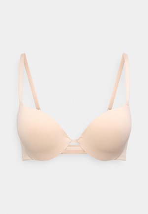 Μπεζ καπιτονέ σουτιέν με ρυθμιζόμενες τιράντες και μικρή λεπτομέρεια κοψίματος ανάμεσα στα cups, εμφανιζόμενο σε ανοιχτό φόντο.