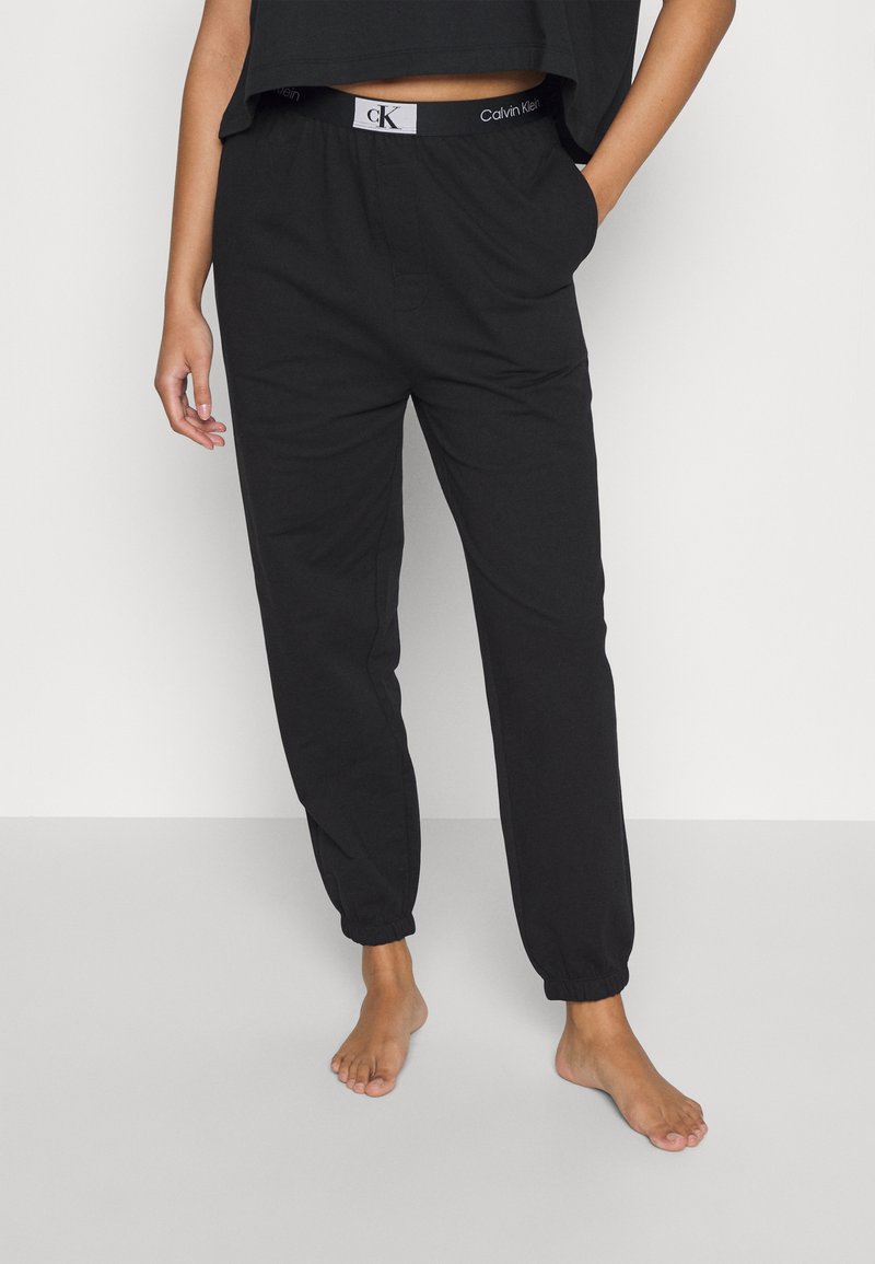 Pantalons de jogging noirs en coton avec des poignets élastiques, une taille à cordon de serrage et un logo Calvin Klein sur la taille. Design minimaliste.