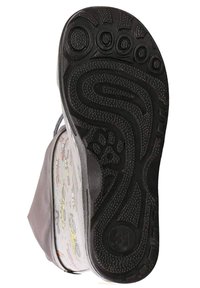 Zwarte rubberen zool met een gestructureerd grippatroon, met een kleurrijk bedrukt inlegzool zichtbaar door het doorschijnende bovenmateriaal.