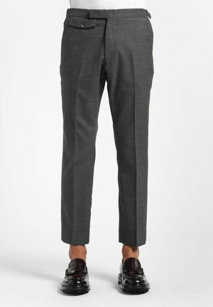 Pantalon tailleur pour homme de couleur gris foncé, longueur raccourcie, plis sur le devant, poches latérales, accompagné de mocassins en cuir noir sur fond blanc.