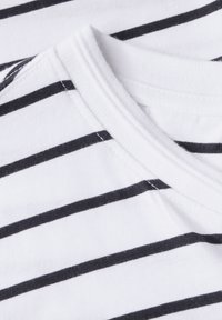 Valkoinen lyhythihainen t-paita, jossa on mustia vaakasuoria raitoja, pyöreä pääntieme ja pehmeä puuvillakangas, jossa on näkyviä ompelut yksityiskohtia.