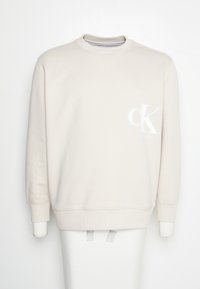 Hellbeige Sweatshirt aus weichem Material, mit Rundhalsausschnitt, langen Ärmeln und einem weißen 'CK'-Logo auf der linken Brust.