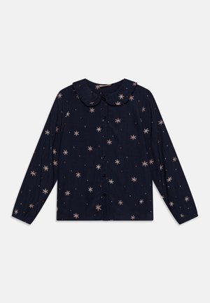 Marinblå skjorta med lång ärm och volangkrage, med ett stjärnmönster i rosa och vitt med små röda detaljer.