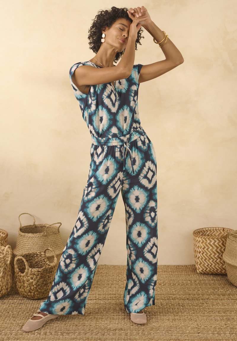Completo a due pezzi con stampa ikat blu e bianca. Il materiale ha una consistenza liscia. Pantaloni a gamba larga con vita elastica e cordino.