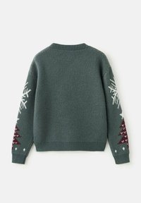 Pull en tricot vert avec un col rond et des manches longues, arborant des motifs de flocons de neige blancs et des motifs d'arbres bordeaux sur les manches.