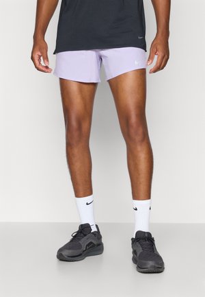 Shorts de sport de culoare mov deschis, tricou negru, șosete albe și adidași negri. Șorturile au o textură netedă și un logo Nike pe lateral.