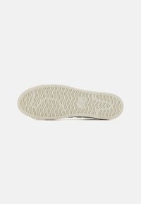 Semelle de chaussure en caoutchouc blanc cassé, avec un motif de vagues texturé pour l'adhérence et la durabilité, design plat avec bords arrondis.