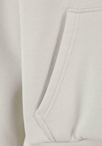 Light gray sweatshirt fabric featuring a pocket with visible stitching. The texture appears soft and slightly stretchy.