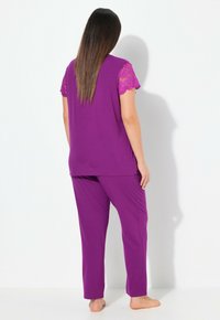 Paarse pyjama set met een effen top met kantaccentmouwen en bijpassende broek in een zachte, gladde stof. Comfortabel en aansluitend voor optimaal draagcomfort.
