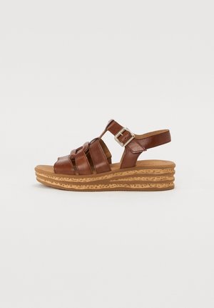 Brun læder sandal med remme, justerbar spænde, polstret fodseng og lagdelt kork kilehælsål.