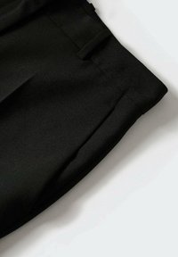 Sorte skræddersyede shorts lavet af glat stof, med et strømlinet snit, forlommer og en pæn kant. Ingen synlig hardware eller mønstre.