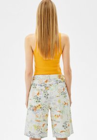 Pantalones cortos ligeros y multicolores con un patrón floral y abstracto, con un corte relajado y cintura de tiro medio. El material parece ser de tela.