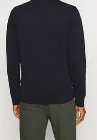 Marineblauwe sweatshirt gemaakt van zachte stof, met een ronde hals, lange mouwen en geribbelde manchetten met een rechte zoom.