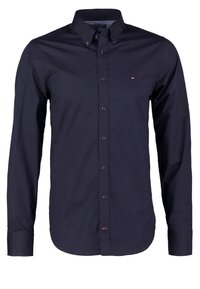 Tmavě modrá ko�šile s knoflíky vyrobená z hladké bavlněné látky, s klasickým límečkem, dlouhými rukávy a malým logem na hrudi.