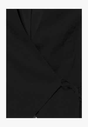 Vêtement noir style portefeuille avec un lien en tissu sur le côté, doté d'un col en V et d'un matériau texturé.