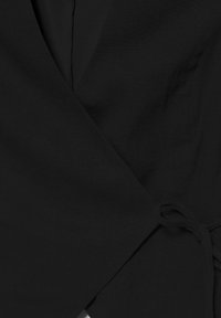 Černý zavinovací oděv s látkovým páskem na boku, vybavený výstřihem do véčka a texturovaným materiálem.