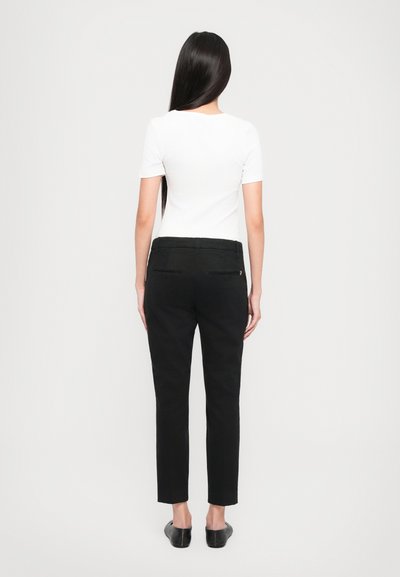 Pantalon noir ajusté avec une texture lisse, comportant deux poches arrières et un design à jambes droites. Associé à un haut blanc uni.