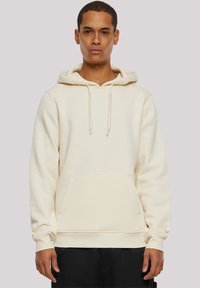 Cream-colored hoodie made of soft fabric, featuring a front pocket, adjustable drawstrings on the hood, and ribbed cuffs and hem.