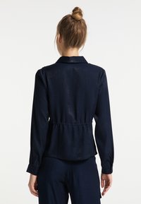 Navy blue button-up shirt gemaakt van lichtgewicht stof, met een getailleerde taille, lange mouwen en een klassieke kraag. Glad textuur met subtiele glans.