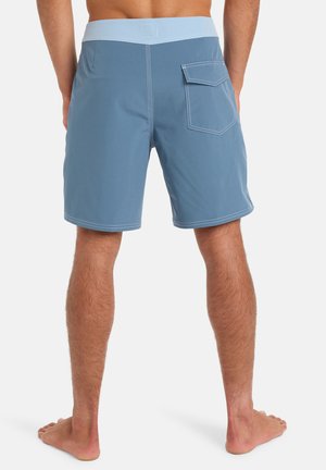 Shorts de bain bleus avec une ceinture bleu clair, présentant une poche arrière et des coutures contrastées. Le matériau semble lisse et léger.