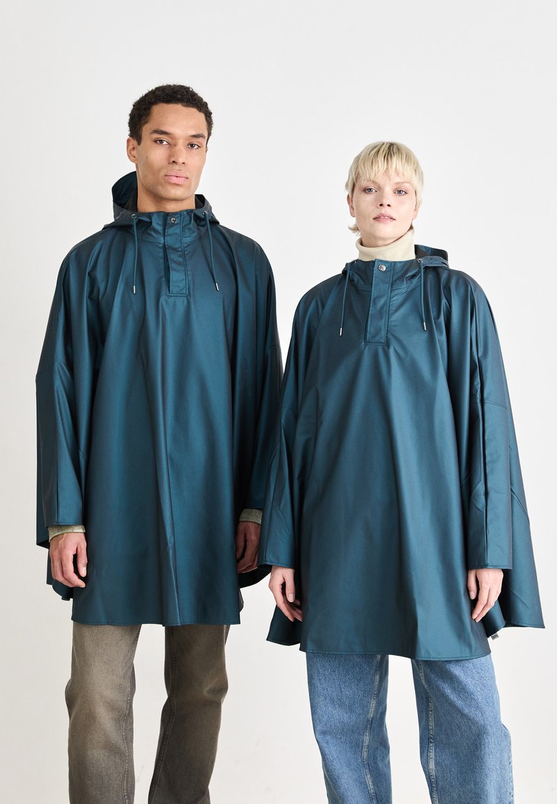 Teal waterproof ponchos with hoods, featuring a front placket and drawstring details. Textured fabric with loose-fitting design.