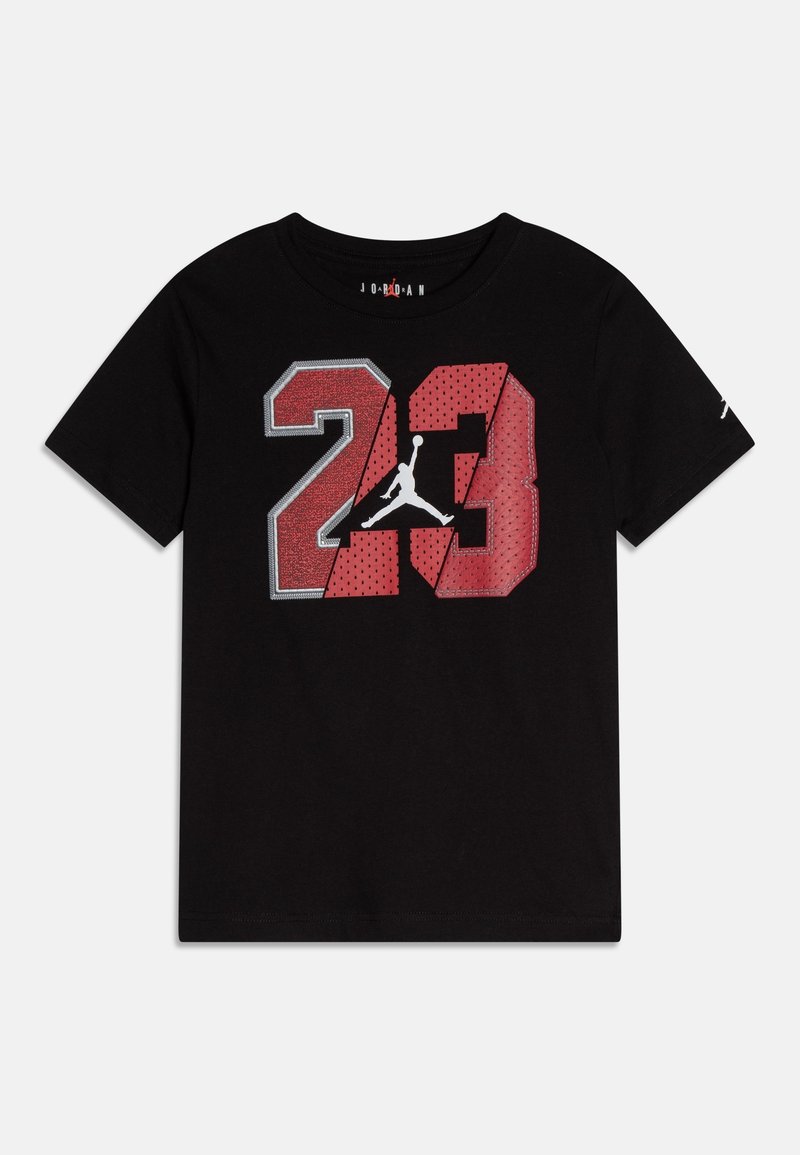 Musta puuvillapaita, jossa on rohkea punainen ja harmaa "23" -grafiikka, jossa on verkkomainen rakenne, valkoinen Jumpman-logo ja pyöreä kaula-aukko.