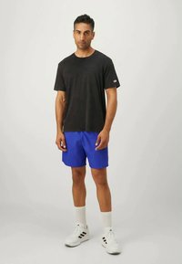 Sort t-shirt med korte ærmer, blå shorts, hvide sneakers med sorte striber og hvide sokker. Simpelt design, afslappet aktivt tøj.