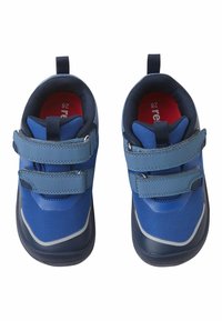 Para niebieskich dziecięcych trampków z podwójnymi zapięciami na rzepy, czarnymi podeszwami i czerwonymi wkładkami, widoczna z góry na białym tle.