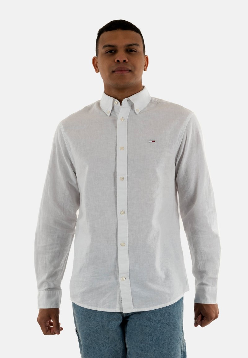 Camicia bianca con collo e maniche lunghe. Realizzata in cotone, presenta un piccolo logo sull'area sinistra del petto.