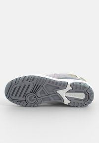 Harmaan sneakerit, joissa on teksturoitu päällinen ja valkoinen välikorko. Kumipohjassa on kuvioitu pito, joka tarjoaa kestävyyttä ja pitoa.