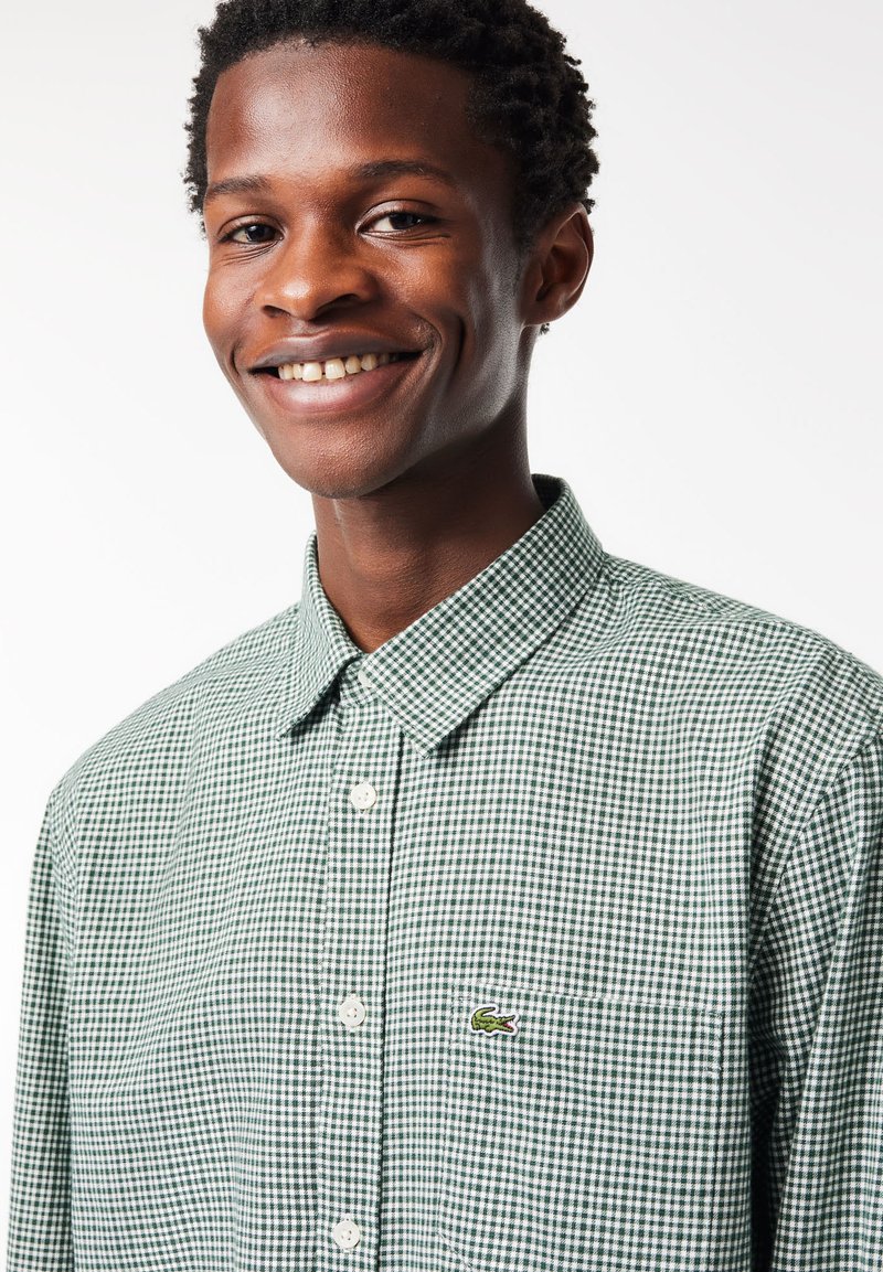 Grün-weißer karierten Hemd mit klassischem Kragen und kleinem gesticktem Logo auf der Brust. Glattes Baumwollgewebe.